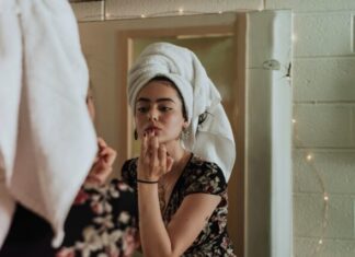 How to Create the Best Natural Skincare Routine woman putting makeup in front of mirror