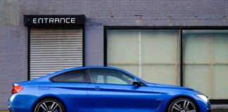 blue coupe beside gray house