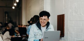 smiling man sitting and using Samsung laptop near people