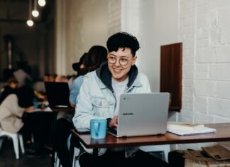 Seven Skills That All Remote Workers Must Possess smiling man sitting and using Samsung laptop near people