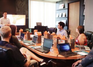 How to choose dedicated development team man standing in front of people sitting beside table with laptop computers