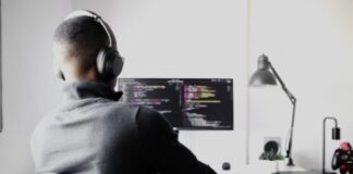 man in black long sleeve shirt wearing black headphones sitting on chair