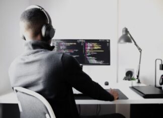 man in black long sleeve shirt wearing black headphones sitting on chair