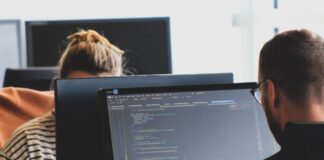 woman in black shirt sitting beside black flat screen computer monitor