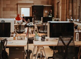 10 Areas to Consider When Planning for Hybrid Workplaces turned off flat screen monitors on top of beige desks
