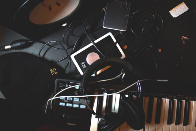 Photo by James Stamler flat-lay photo of headphones, MIDI keyboard, and speaker on black surface