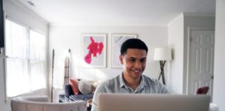 man in gray hoodie sitting on chair in front of silver macbook