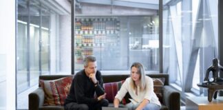 man and woman sitting on couch using macbook