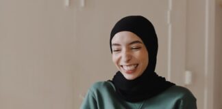 woman in green hijab holding white ceramic mug