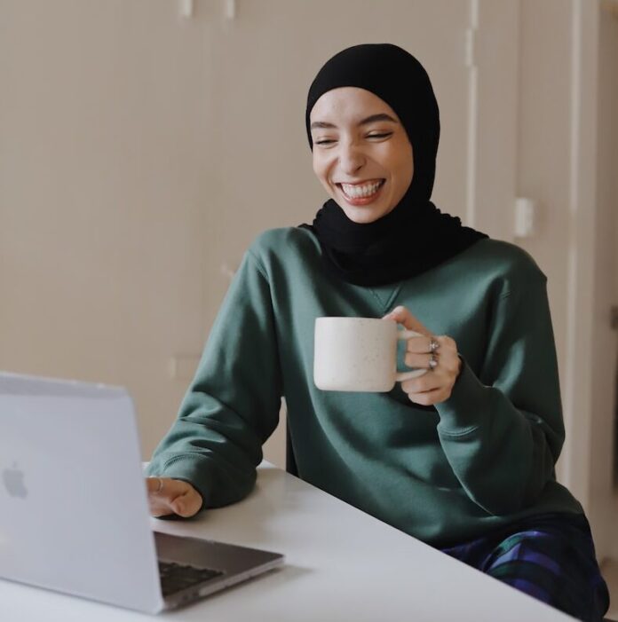 Photo by Good Faces woman in green hijab holding white ceramic mug