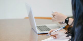 person holding pen writing on paper