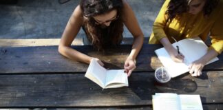 woman reading book while sitting on chair
