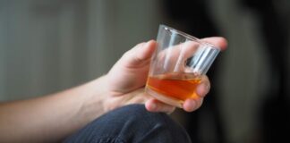 person holding clear drinking glass with orange liquid