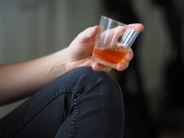 Photo by Sean Bernstein person holding clear drinking glass with orange liquid