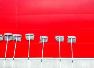 Carpet cleaning in a Austin, Texas hospital by The Steam Team of Austin and laundering surgical scrub caps in commercial washing machines seven white push mops on wall