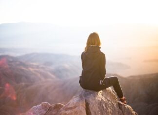 How to Get Existential Chaos Under Control? person sitting on top of gray rock overlooking mountain during daytime