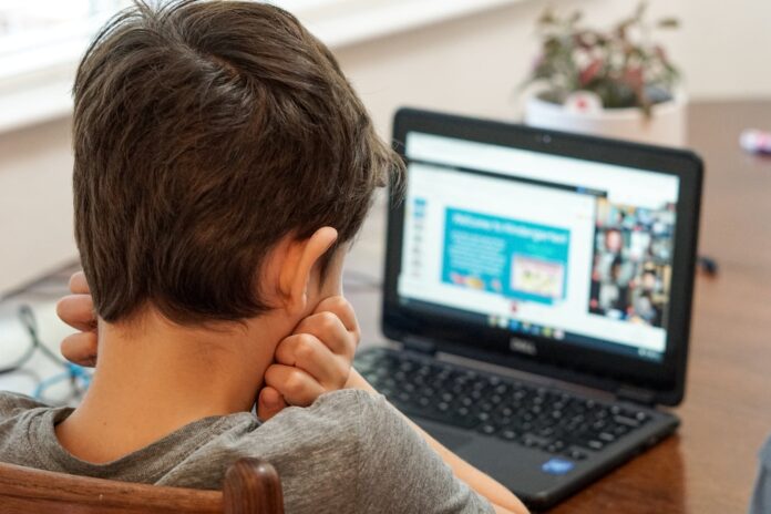 Photo by Thomas Park boy in gray shirt using black laptop computer