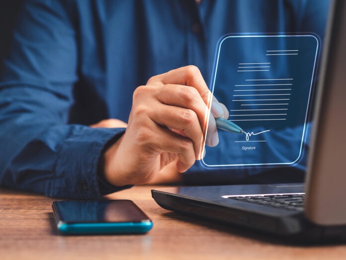 A businessman using a pen signing electronic documents on digita