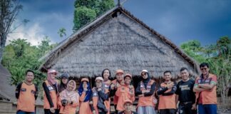 group of people standing near brown wooden house