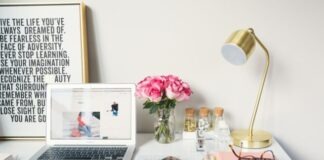 MacBook Air beside gold-colored study lamp and spiral books