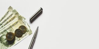 gray pen beside coins on Indian rupee banknotes