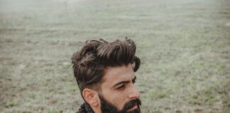 man in black leather jacket standing near body of water during daytime