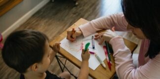 boy in white long sleeve shirt writing on white paper