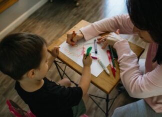 boy in white long sleeve shirt writing on white paper