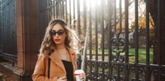 woman in brown coat holding white cup