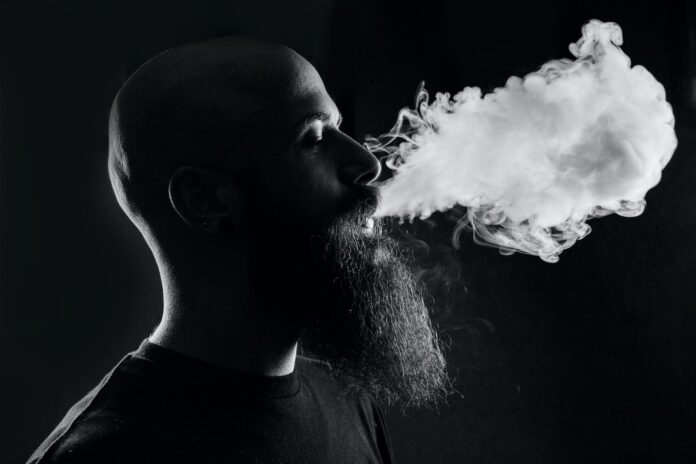 Photo by Quinten de Graaf man smoking with black background