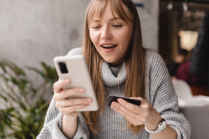 Happy young blonde woman with bang customer shopper holding cred