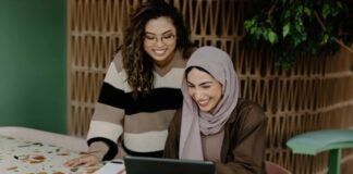 Two women sitting at a table with a laptop