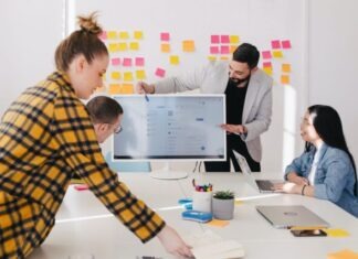 How to Build a Happy and Productive Team: Consolidation Tips man standing behind flat screen computer monitor