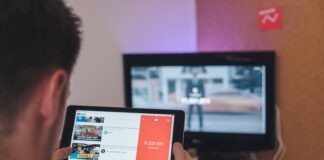 man browsing tablet sitting in front of TV