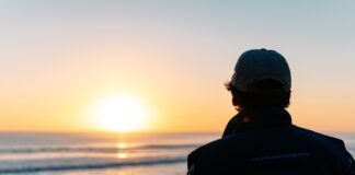 a man looking out at the ocean at sunset