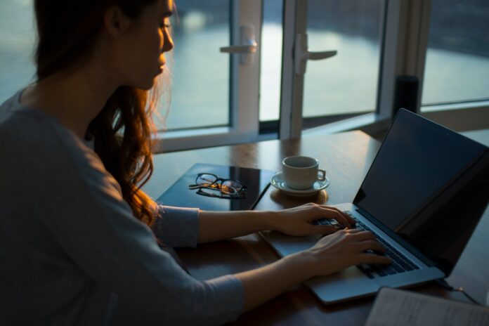 Photo by Thought Catalog woman sitting beside table using laptop