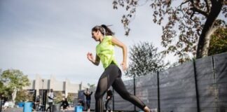 woman in green tank top and black leggings doing yoga on blue round trampoline