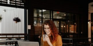 woman in brown long sleeve shirt sitting by the table using macbook