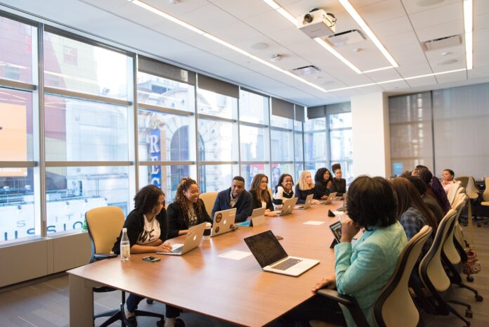 Photo by Christina @ wocintechchat.com group of people sitting beside rectangular wooden table with laptops