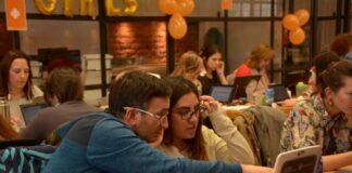 a group of people sitting at a table with laptops