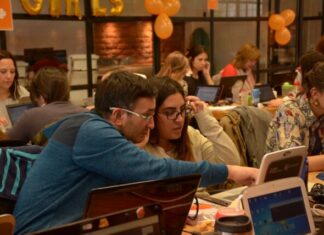 a group of people sitting at a table with laptops