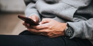 person in gray sweater wearing black and silver chronograph watch