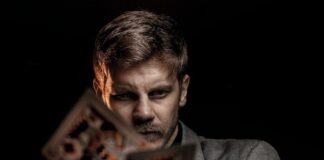 man in gray suit jacket holding jack of diamonds playing card