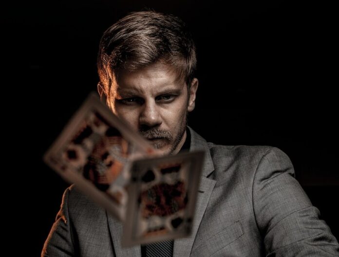 Photo by Alexander Jawfox man in gray suit jacket holding jack of diamonds playing card