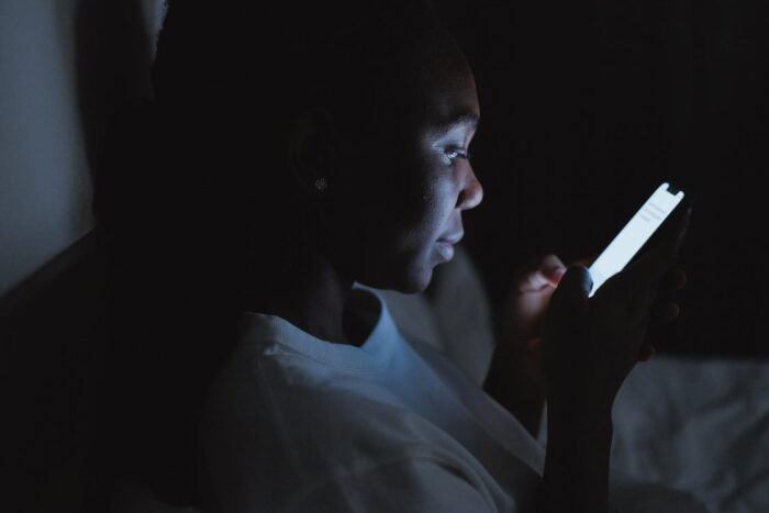 Free Woman in White Shirt Using Smartphone in Dark Room Stock Photo