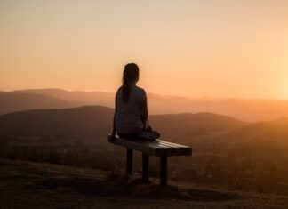 Mindfulness Made Easy with KALM: A Comprehensive Guide woman sitting on bench over viewing mountain