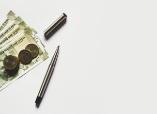 gray pen beside coins on Indian rupee banknotes