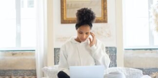 A person sitting on a bed using a computer Description automatically generated