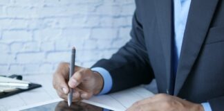 a man in a suit writing on a tablet