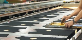 a person cutting fabric on a conveyor belt